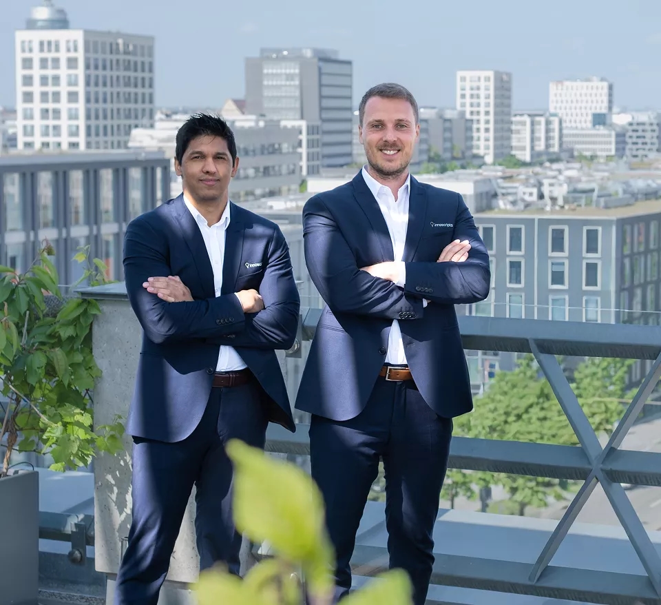 Three business professionals in formal attire standing confidently on a rooftop with a cityscape in the background