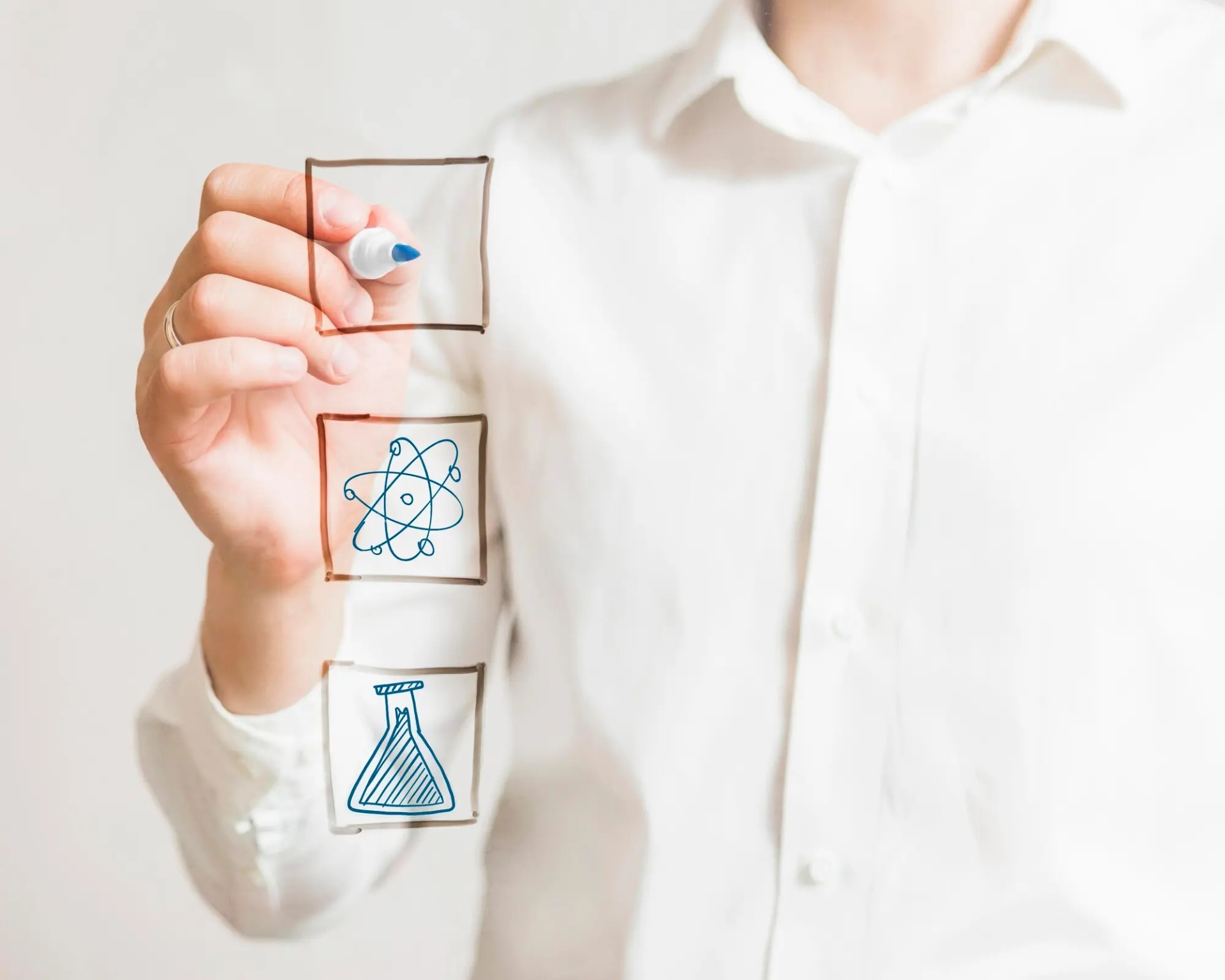 A person writing on a glass with a marker, symbolizing the process of innovation and creativity